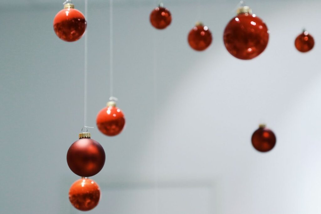 Red Christmas balls hanging against a white backdrop, capturing festive elegance.