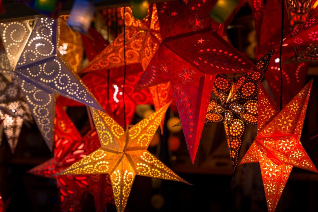 Vibrant star-shaped paper lanterns beautifully lit up, typical of German Christmas markets.