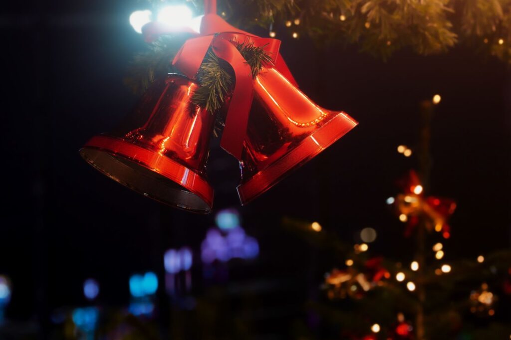 Red Christmas bells with ribbons and lights create a festive holiday atmosphere.